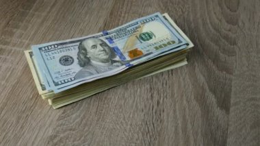 Eller ahşap masada yığınla dolar katlar. Bir banknottan diğerine. Belki de birikimlerini aktarıyordur ya da kar yapıyordur. Yakın plan..
