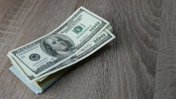 Hands fold many dollars in stack on wooden table. One banknote after another. Maybe he is recounting his savings or making a profit. Close-up. — Stock Video