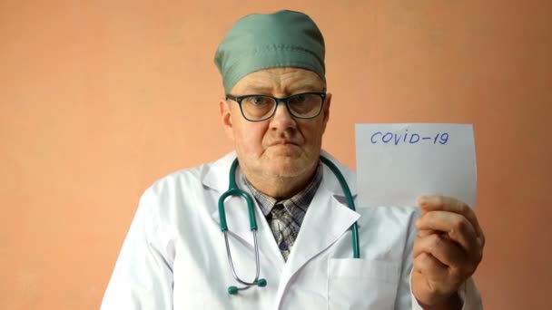 Boze dokter van Kaukasische etniciteit, in witte labjas, verheugt zich, en glimlacht naar het feit dat hij veel geld kan hebben als gevolg van de epidemie van het coronavirus of covid-19. Close-up. — Stockvideo