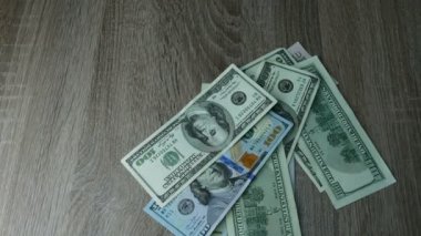 Eller ahşap bir masanın üzerine bir sürü dolar saçar. Yakın plan..