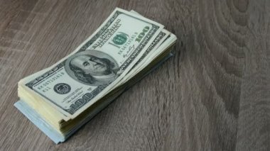 Eller ahşap masada yığınla dolar katlar. Bir banknottan diğerine. Belki de birikimlerini aktarıyordur ya da kar yapıyordur. Yakın plan..