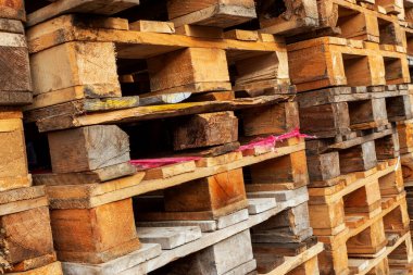 Deponun üzerinde kullanılmış ahşap palet yığınları geri dönüşüme hazır. Endüstriyel geçmiş. Yakın plan. Açık havada..