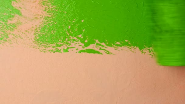 La mano humana pinta la pared rosa en color verde brillante con rodillo de pintura. Primer plano . — Vídeo de stock