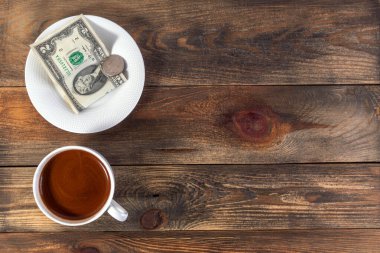 Canlandırıcı espresso, kahve ve çay tabağı ile birlikte iki Amerikan doları ve parası. Koyu ahşap arka planda. Ödeme ya da bahşiş. Üst Manzara. Uzayı metin için kopyala. Düz yatıyordu. 