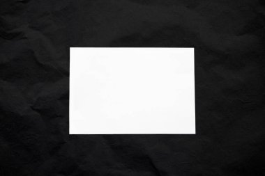 Siyah buruşuk bir arkaplanda boş beyaz çerçeve. Sevdiğiniz birini kaybettiğiniz için yas tutma konsepti ya da ölüm ilanı için yer. Soyut arkaplan. Yakın plan..