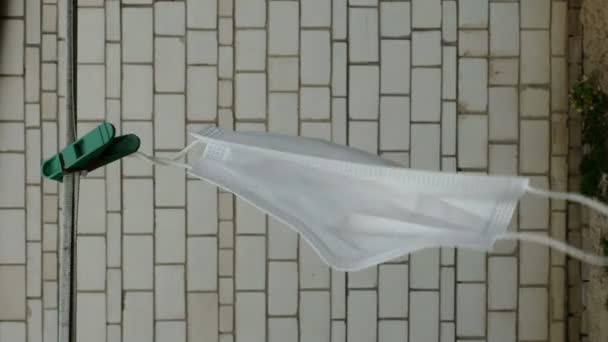 Medische masker droogt op waslijn in de binnenplaats van huis of ziekenhuis, zwaait in de wind. Concept schaarste van medische maskers tijdens coronavirus epidemie en moeten ze vele malen te gebruiken. Verticaal. — Stockvideo