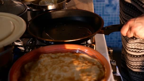 Vrouwelijke handen bakken pannenkoeken in koekenpan en draaien ze, op fornuis thuis in de keuken. Middelgroot plan. — Stockvideo
