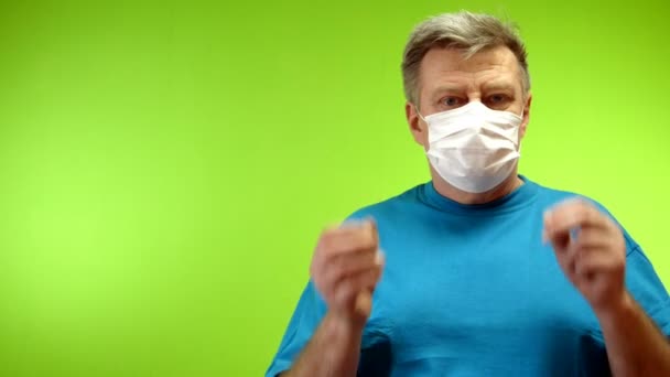 Homem adulto sênior positivo tira sua máscara médica protetora que proteção coronavírus fora e piscar de olhos. Otimismo e amor à vida. Fundo verde. Chromakey. Close-up . — Vídeo de Stock