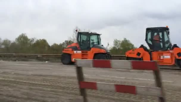 Kiev, Oekraïne april 2020: - Wegenwerken, wegenbouw. Werkzaamheden van de bouw apparatuur, mechanismen voor reparatie en aanleg van asfalt bestrating. Van van bewegende auto. — Stockvideo