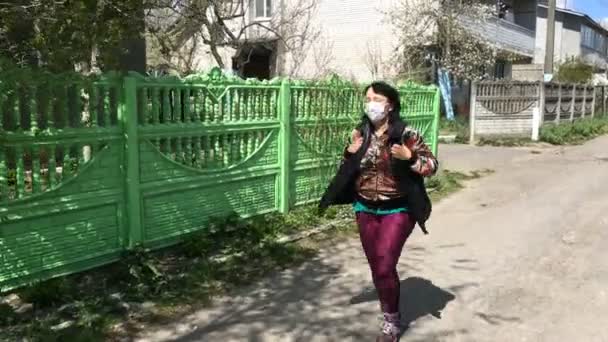 Mujer mayor activa en máscara médica para la protección contra el virus, corriendo por la carretera en la calle vacía. Deporte en cuarentena. Plan general . — Vídeo de stock