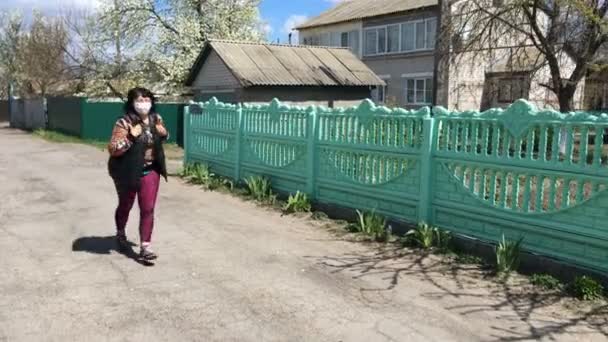 Senior actieve vrouw met medisch masker voor bescherming tegen het virus, rennend langs de weg op lege straat. Sport op quarantaine. Algemeen plan. — Stockvideo