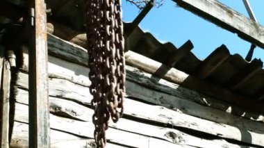 Eski paslı metal zincirler terk edilmiş atölyede ya da sanayi bölgesinde rüzgarda sallanıyor. Yakın plan..