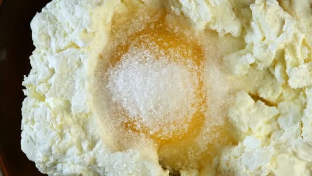 Σπιτική μαγειρική. Λιπαρά φρέσκο τυρί cottage μείγμα με ωμό αυγό και ζάχαρη από dint του ξύλινη κουτάλα. Γεμίστε το φαγητό. Κοντινό πλάνο. — Αρχείο Βίντεο