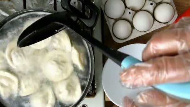 Dumplings are removed from cooking pan with boiling water with slotted spoon, put in white bowl and greased with butter. Homemade kitchen. Top down food. Flat lay. Top view. — Stock Video