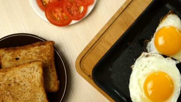 Gefrituurde eieren worden op geroosterd brood met keukenspatel uit een koekenpan gelegd. Voedsel van boven naar beneden. Plat gelegd. Sluiten.. — Stockvideo