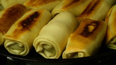 Lezzetli, sarılmış, iştah açıcı krepler kızartma tavasında kızartma yağıyla kızartılır. Ev yapımı yemek pişirmek. Yakın plan. Kapalı.