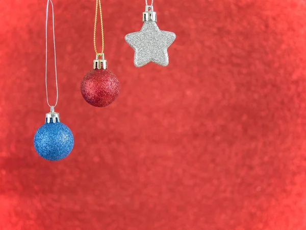 Estrela de prata e vermelho, bola de Natal azul pendurar no backgr borrão vermelho — Fotografia de Stock