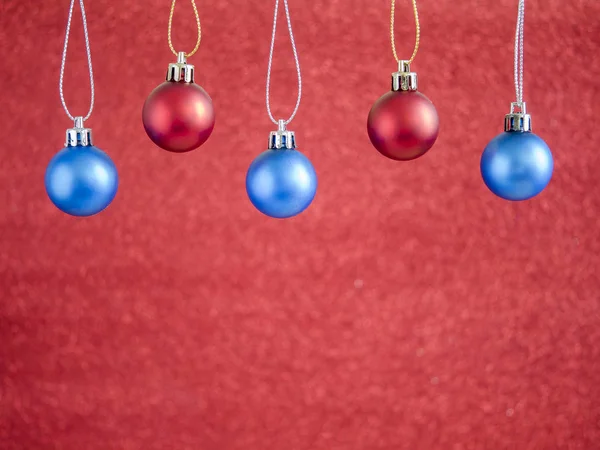 Bola de Natal vermelho e azul pendurar no fundo borrão vermelho 1 — Fotografia de Stock