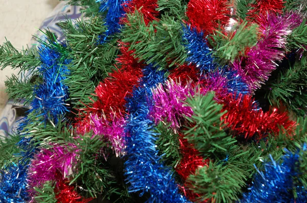 Christmas toy hanging on the Christmas tree surrounded by multi-colored tinsel. — Stock Photo, Image