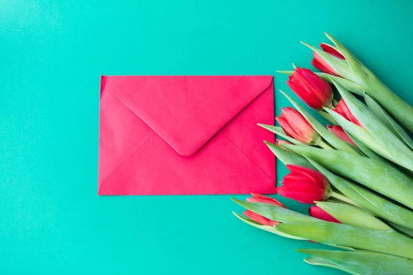 Красный букет тюльпанов и конверт — стоковое фото
