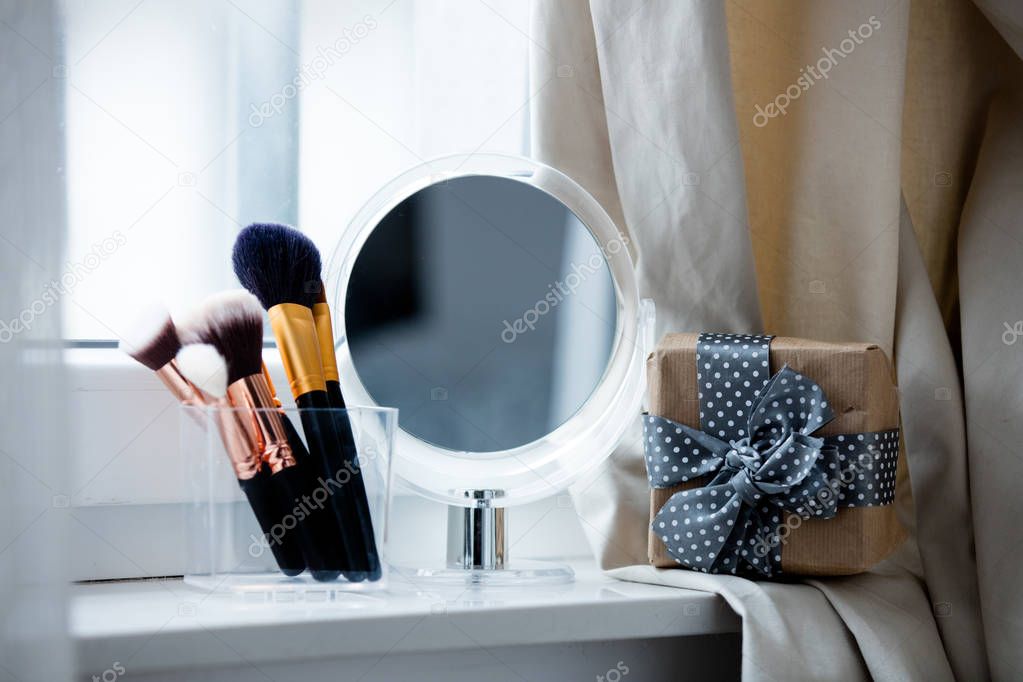makeup brushes and mirror on windowsill