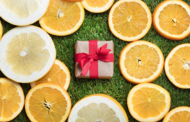 Yeşil çimenlerin üzerinde hediye ve portakal dilimleri 