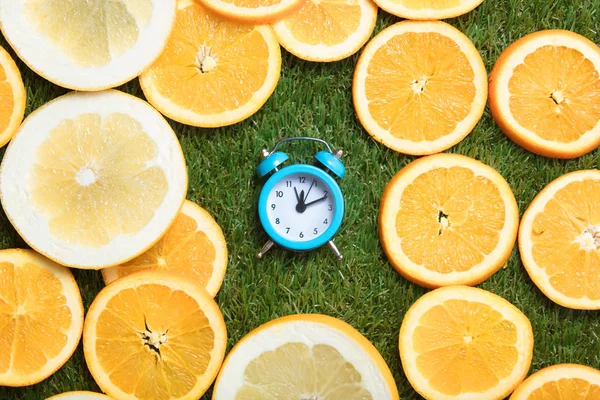 Sveglia e fette arancioni su erba — Foto Stock