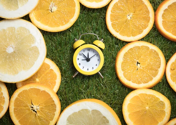 Wecker und Orangenscheiben auf Gras — Stockfoto