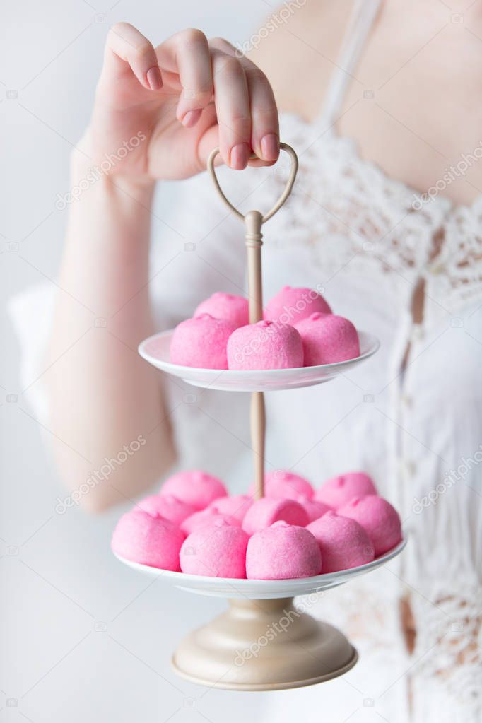 photo of young woman holding stand with pink marshmallows on the