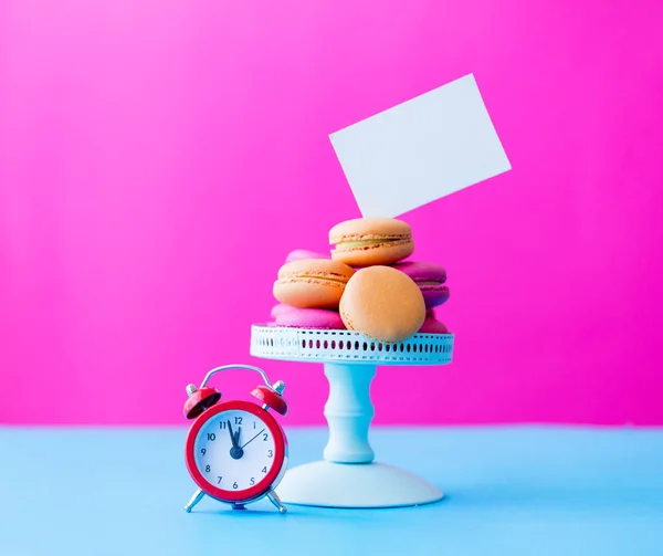 Macaroons em stand com despertador vintage — Fotografia de Stock