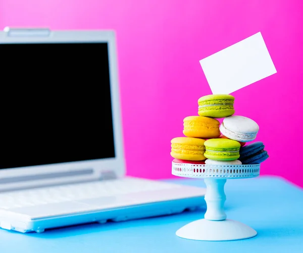 Macaroons em stand com computador portátil — Fotografia de Stock