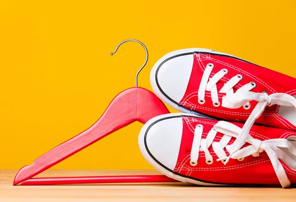 Red sporty gumshoes and clothes hanger — Stock Photo, Image