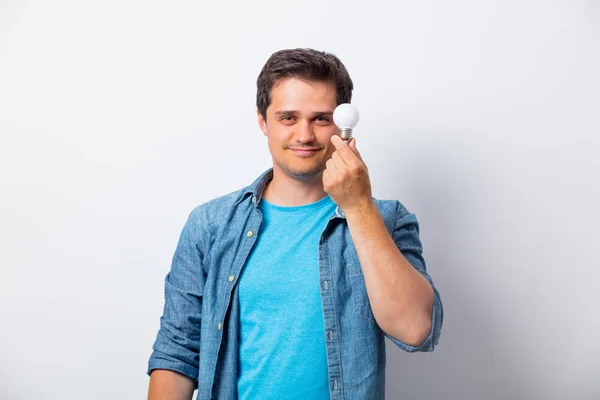 Jovem de camisa segurando bulbo — Fotografia de Stock