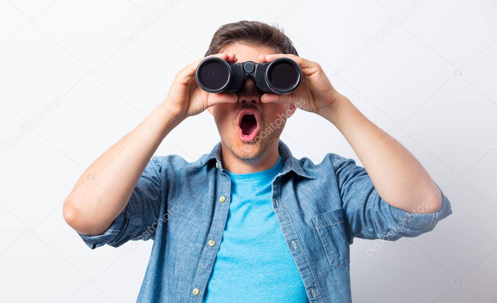 Young man seeking with binocular something 