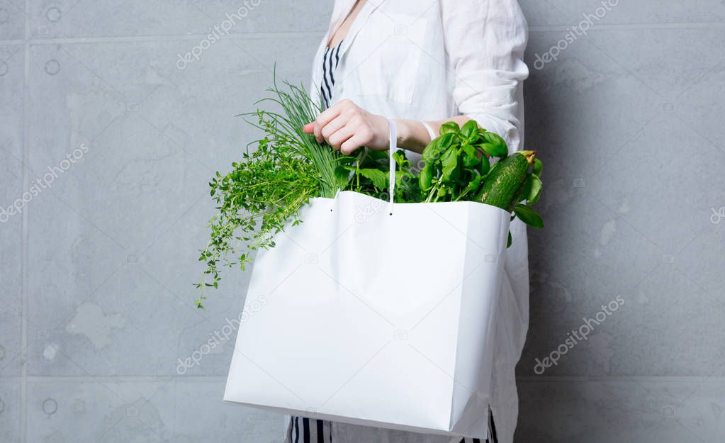 woman holding white bag with herbs