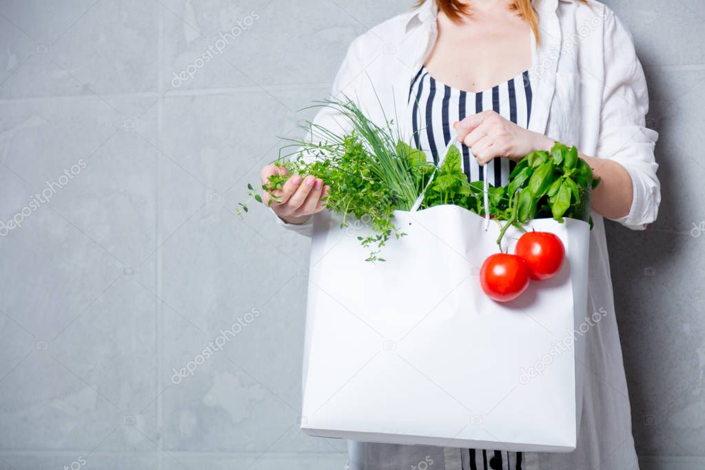 woman holding bag with herbs and tomatoes