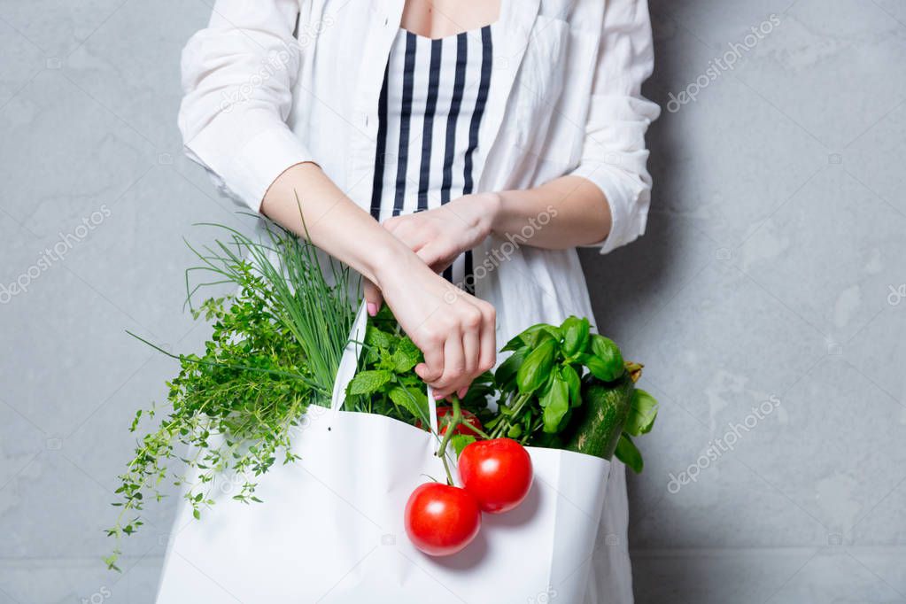 woman holding bag with herbs and tomatoes