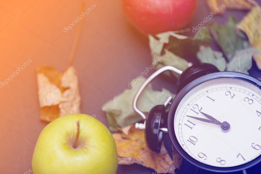 Apples and leaves with retro alarm clock