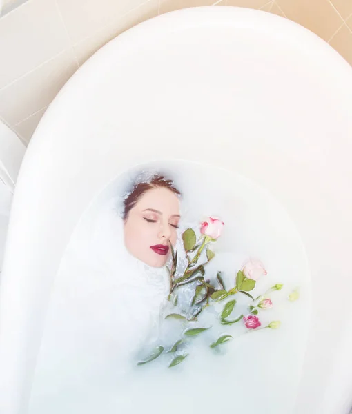 Femme avec des fleurs roses dans le bain de mousse — Photo
