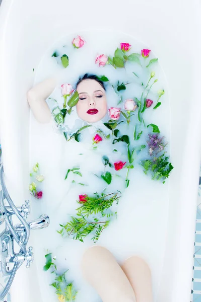 Femme avec des fleurs roses dans le bain de mousse — Photo