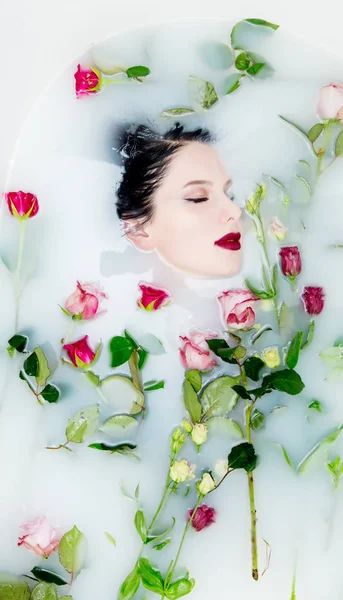 Femme avec des fleurs roses dans le bain de mousse — Photo