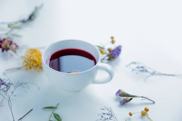 Tasse blanche de thé rouge et d'herbes aux fleurs — Photo