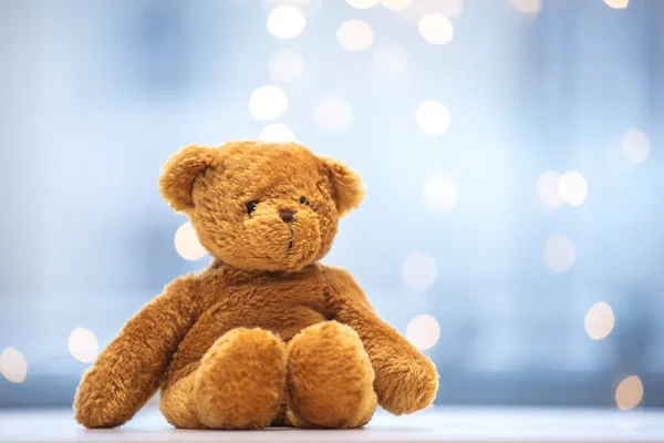 Teddy bear soft toy on fairy lights — Stock Photo, Image