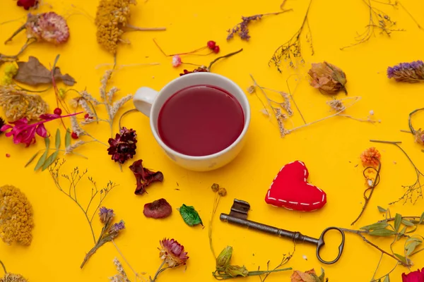 Tasse de thé rouge en forme de coeur et clé vintage et herbes — Photo