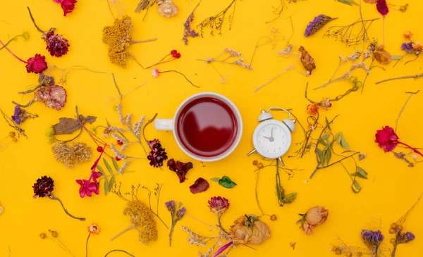 Чашка красного чая с будильником и травами — стоковое фото