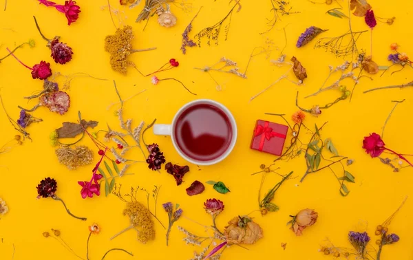 Kopp rött te med presentask och örter med blommor — Stockfoto