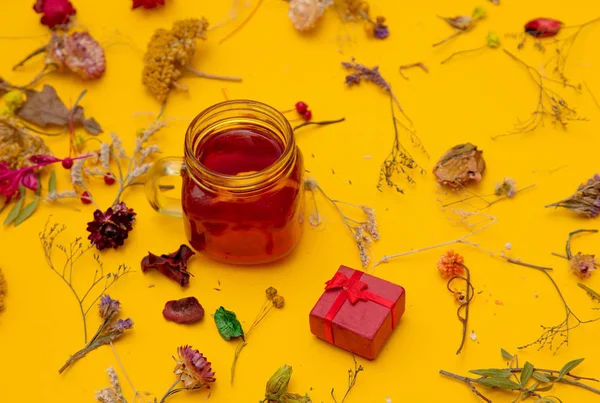 Xícara de chá vermelho com caixa de presente e ervas com flores — Fotografia de Stock