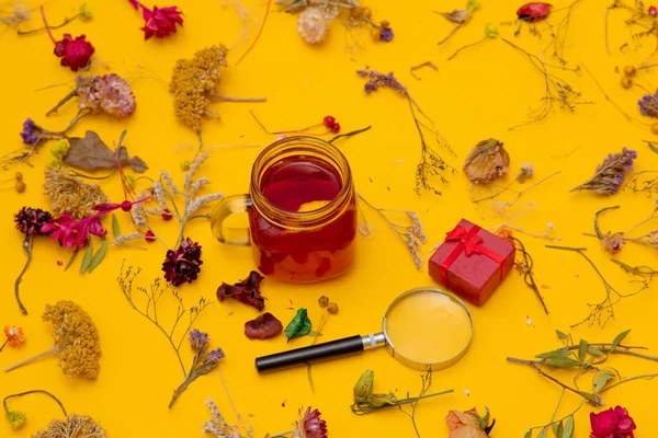 Xícara de chá vermelho com caixa de presente, maquilhagem e ervas — Fotografia de Stock