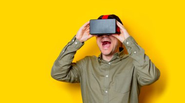Vr gözlük kullanan genç adam. Portre Sarı zemin üzerine