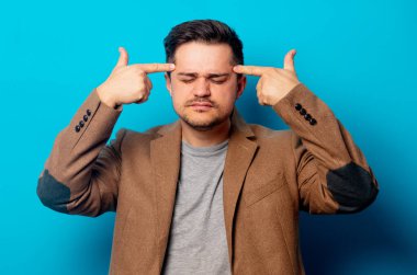 Mavi arka planda baş ağrısı olan bir adam. 